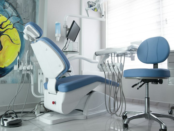 A treatment room with a dental chair beside a window.
