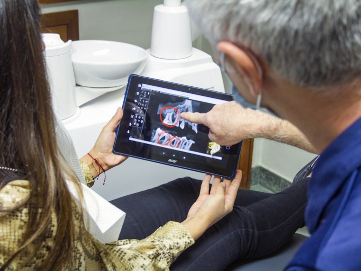 A dentist showing a patient their dental X-ray on a tablet.